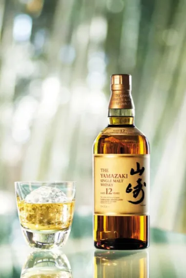 A bottle of Yamazaki whisky beside a glass of whisky on the rocks